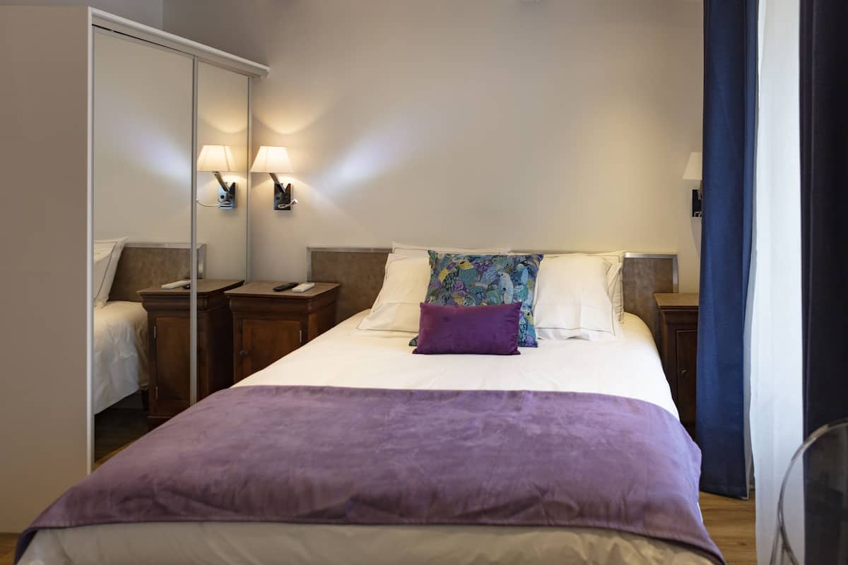 Ein Hotelzimmer mit einem großen Bett, einem Kleiderschrank, Nachttischen und einem Spiegel.