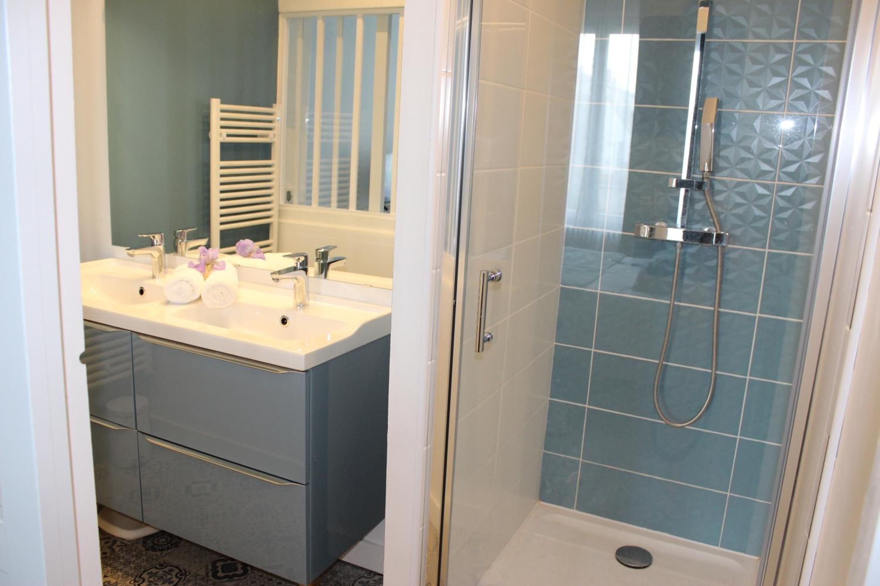 A bathroom with a glass-enclosed shower, a double sink vanity, and a towel rack.