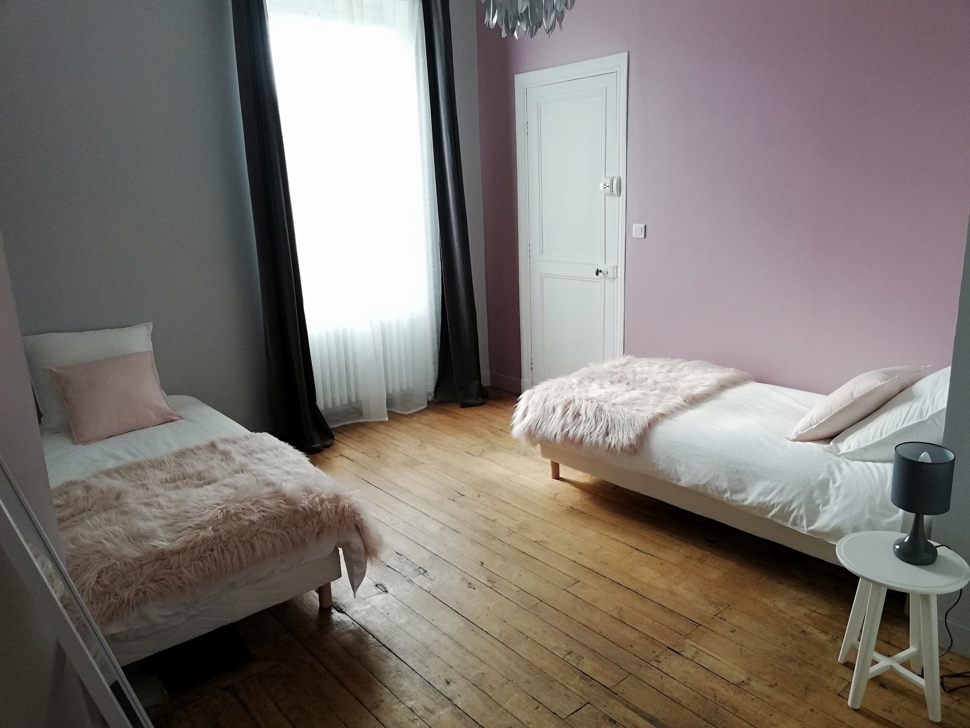Un dormitorio con dos camas, una puerta blanca y un taburete pequeño.