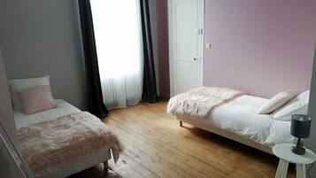 Un dormitorio con dos camas, una puerta blanca y un taburete pequeño.