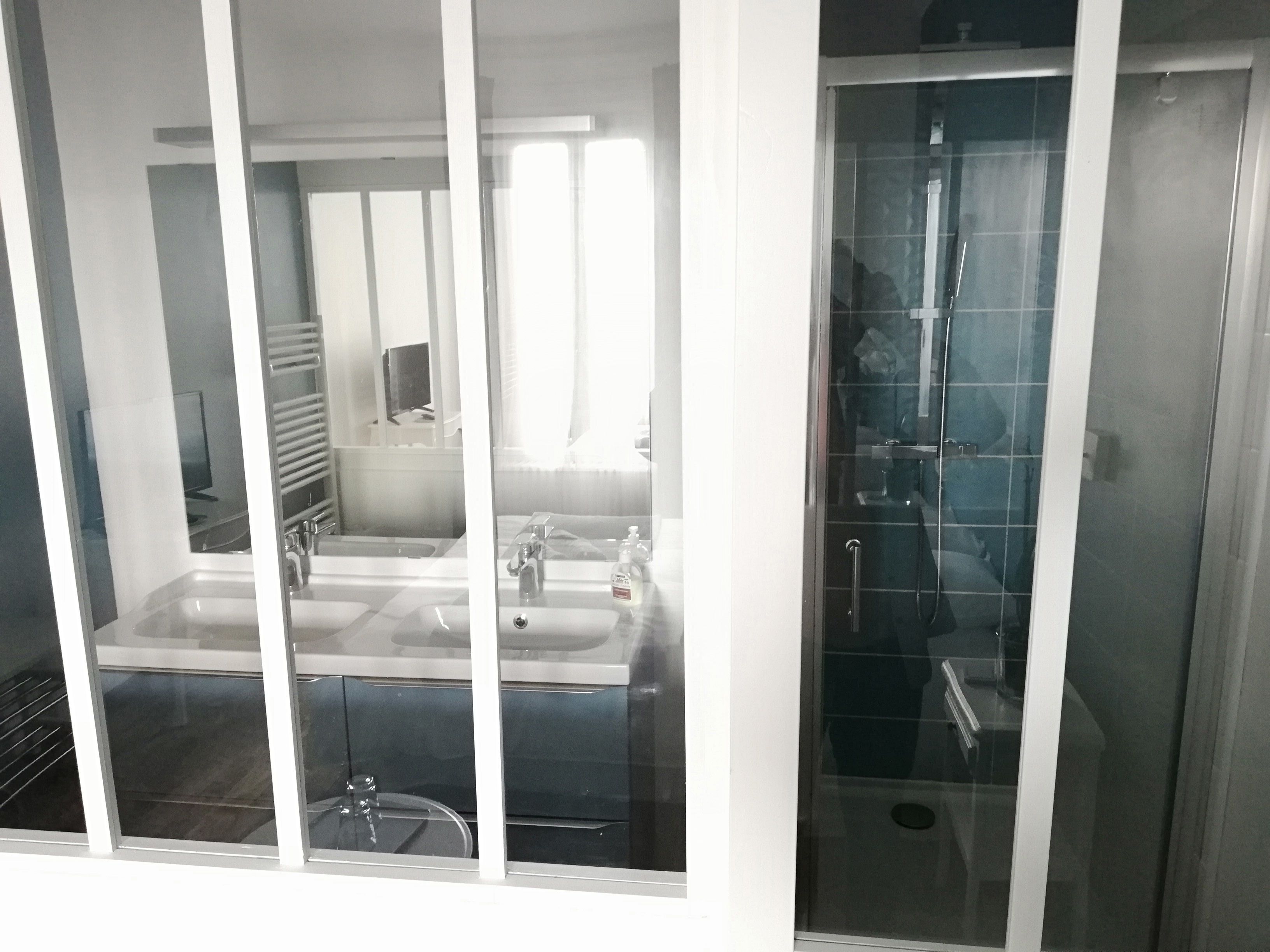 Une salle de bain avec une douche à parois de verre, un lavabo et un miroir.