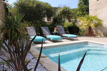 Una piscina al aire libre de temporada, sillones reclinables de piscina