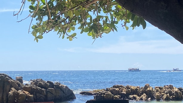 A beachside view with rocky formations, clear blue water, and a distant boat. - Oasis Wadduwa (Wadduwa)