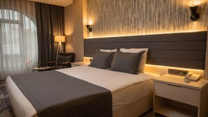 Ein Hotelzimmer mit einem großen Bett, Nachttischen, einer Lampe und einem Telefon.