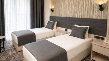 Habitación de hotel con dos camas, una mesita de noche, un teléfono y una lámpara fijada a la pared.
