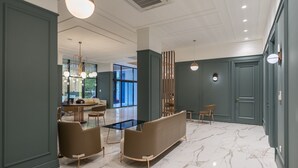 Eine großzügige Lobby mit Marmorboden, einer Couch, einem Couchtisch und einem Essbereich mit Stühlen und Tisch.