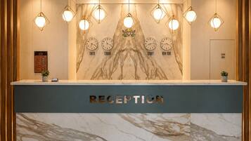 A reception desk with a marble counter, multiple wall clocks, and hanging pendant lights.