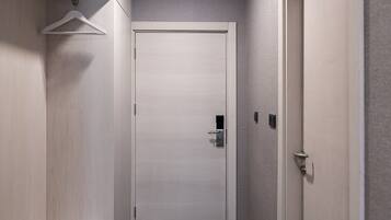 A narrow hallway with a bench, a coat rack, and a door at the end.