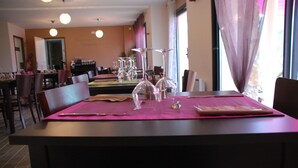 Comedor con mesas dispuestas para dos personas, con copas de cristal transparente y cubertería.
