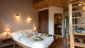 Un dormitorio con una cama de madera, lámparas de noche, un armario de madera y una escalera de madera.