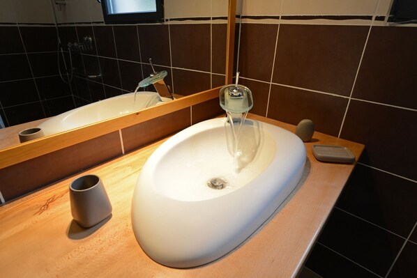 A modern bathroom with a white sink, a handheld showerhead, and a mirror above the sink. - Lauz'oustal - Maison d'hôtes (Montrodat)
