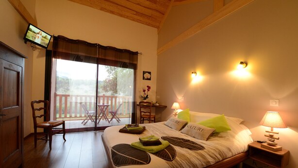 Un dormitorio con una cama de madera, un escritorio con lámpara, una silla y un televisor en la pared.