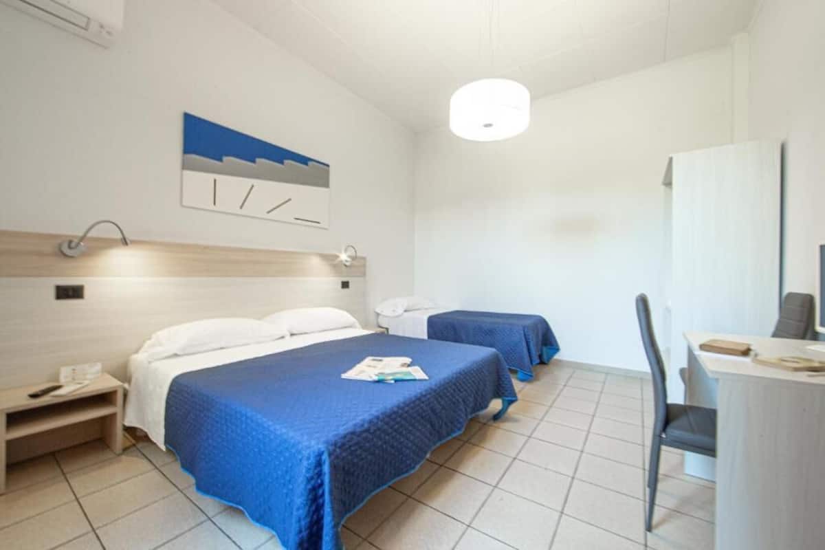 Une chambre d’hôtel avec deux lits, un bureau et une chaise.