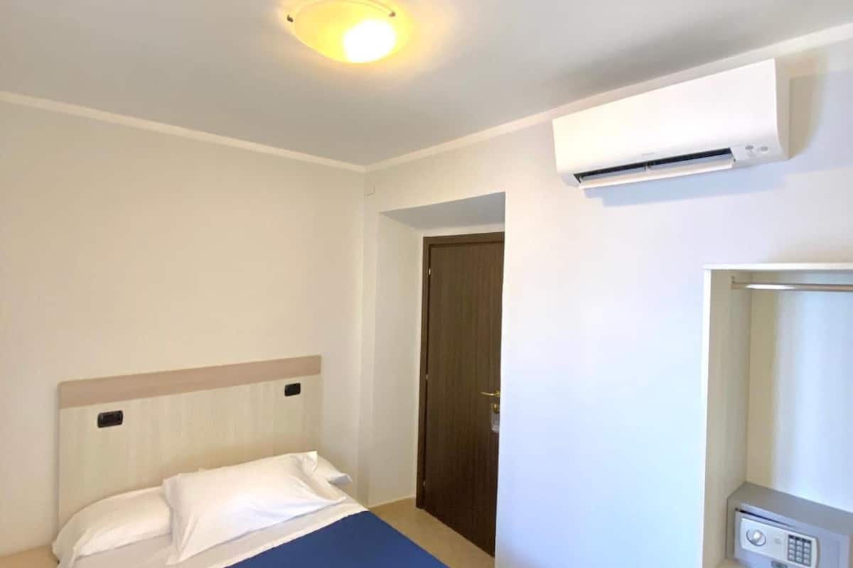 Une chambre d’hôtel équipée d’un lit, d’un appareil de climatisation, d’une armoire et d’une porte.