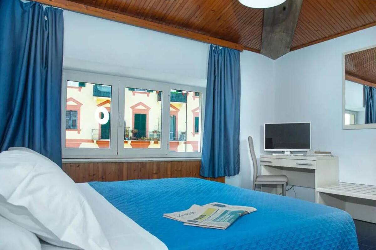 Une chambre d’hôtel avec un lit, un bureau, une chaise et une fenêtre avec des rideaux.