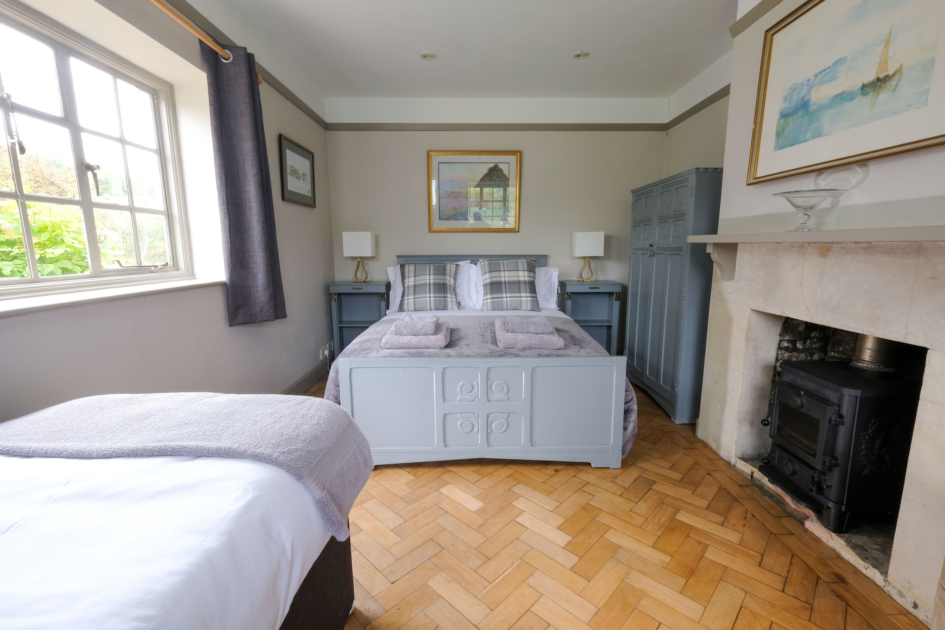 A bedroom with a bed, bedside tables, a fireplace, and a window.