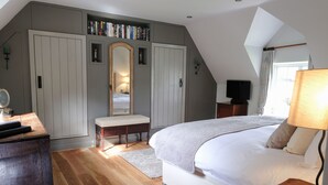 Une chambre à coucher avec un grand lit, un bureau en bois, une bibliothèque et un téléviseur.