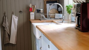 Une cuisine avec un plan de travail en bois, des placards blancs, un évier et un four à micro-ondes.