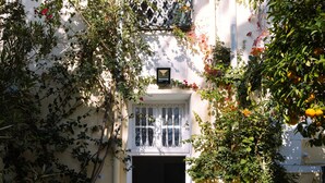 A building with a white facade, a lattice window, and a door leading to an interior. - L'appartement du Palais (La Marsa)