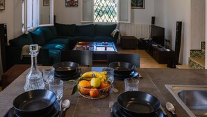 A dining area with a table set for four, a fruit basket, and a sofa in the background. - L'appartement du Palais (La Marsa)