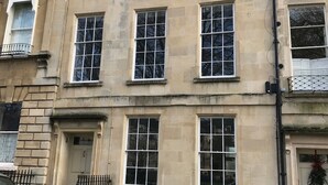 Ein mehrgeschossiges Gebäude mit einer symmetrischen Fassade, das gleichmäßig verteilte Fenster und einen zentralen Eingang zeigt.