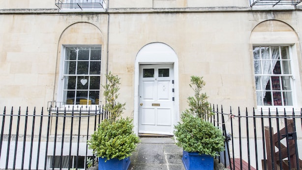 A building with a white door, two windows with heart-shaped decorations, and a black iron fence. - River View (Bath)