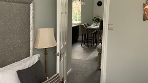 A bedroom with a bed, a nightstand, a lamp, and a view into the dining area. - River View (Bath)
