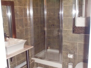 A bathroom with a glass-enclosed shower, a sink, and a toilet. - River View (Bath)