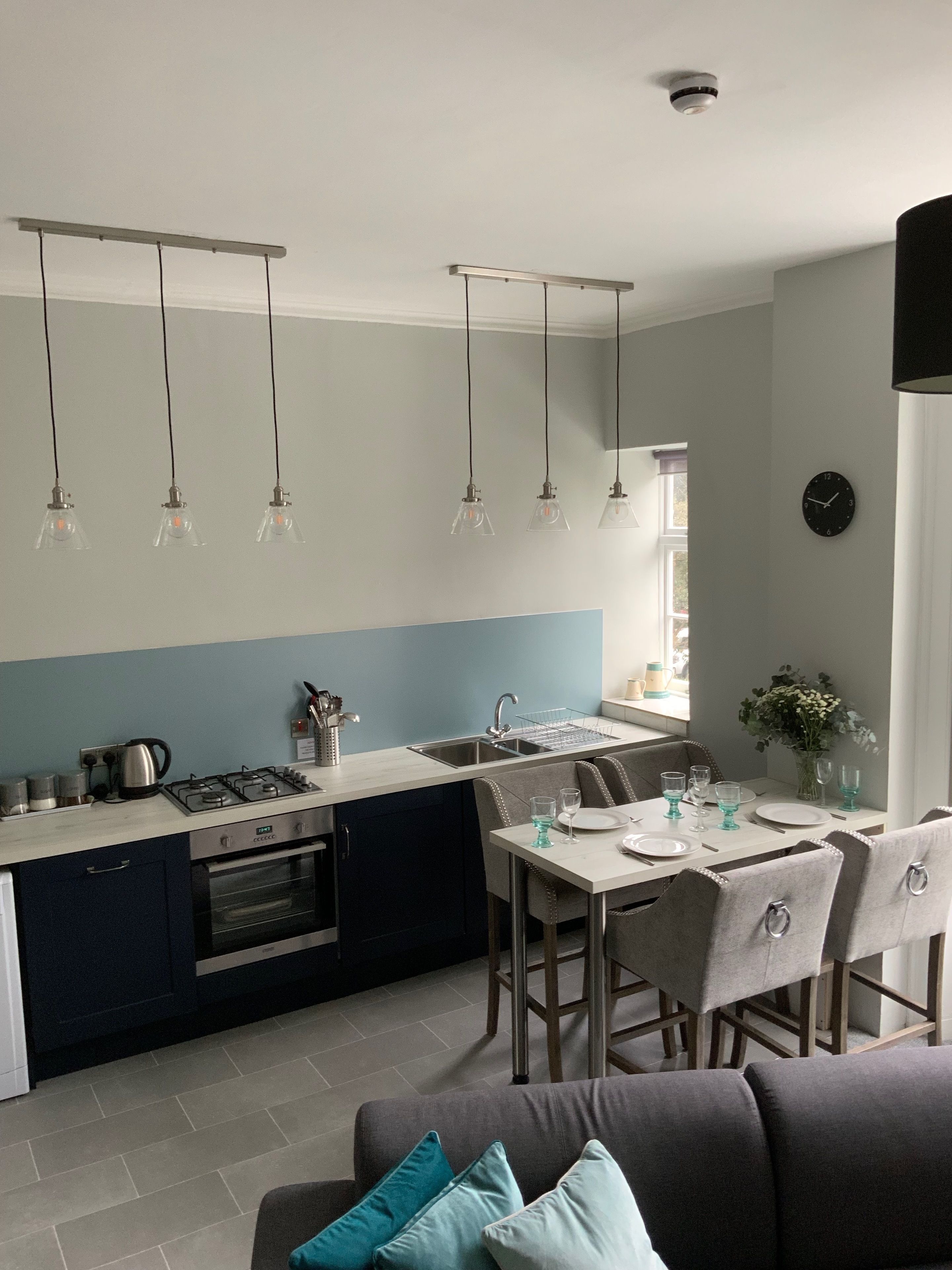 A modern kitchen with a gas stove, sink, and a dining area with a table set for two.