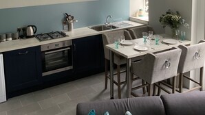 A modern kitchen with a gas stove, sink, and a dining area with a table set for two. - River View (Bath)