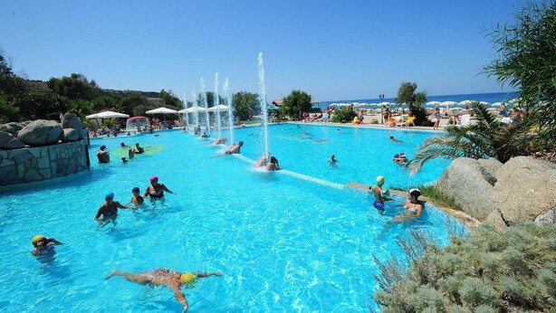A large outdoor swimming pool with multiple water features and people swimming. - Hotel Residence Solemare (Ricadi)