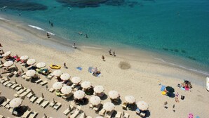 A beach with rows of sun loungers and umbrellas, a clear blue sea, and a few people swimming. - Hotel Residence Solemare (Ricadi)