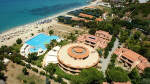 An aerial view of a resort with a central circular building, a swimming pool, and a beach area with umbrellas. - Hotel Residence Solemare (Ricadi)