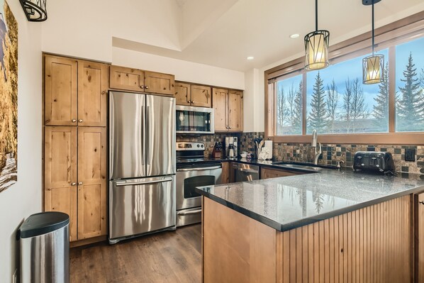 Kitchen features a large island with a sleek countertop, stainless steel appliances, and ample storage.