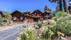 Un grand chalet en bois à plusieurs étages, doté d’une entrée imposante et d’une allée menant au bâtiment principal.