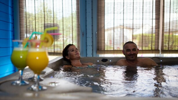 Twee personen in een jacuzzi met drankjes.