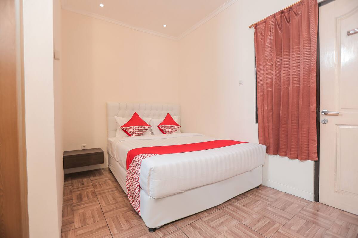 A bedroom with a bed, a nightstand, and a door.