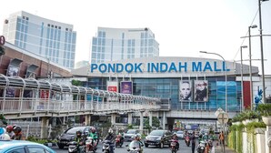Una calle concurrida con un edificio grande que dice "PONDOK INDAH MALL".