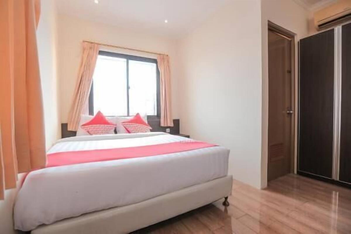 A bedroom with a bed, a window with curtains, a wardrobe, and a door.