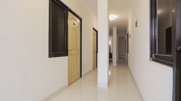Un pasillo limpio y bien iluminado, con paredes y puertas blancas, que conduce a otras habitaciones.