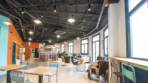 A spacious cafe with high ceilings, large windows, and a variety of seating options including tables and chairs. - Safestay Barcelona Passeig de Gracia (Barcelona)