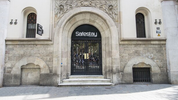 A Safestay hotel entrance with a black gate, stone archway, and a sign above the door. - Safestay Barcelona Passeig de Gracia (Barcelona)