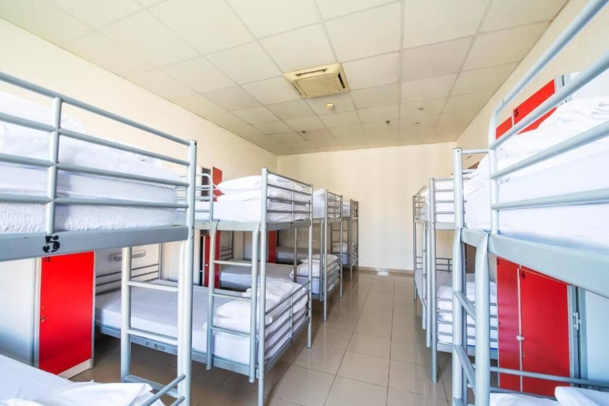 A dormitory room with bunk beds, red lockers, and a tiled floor.