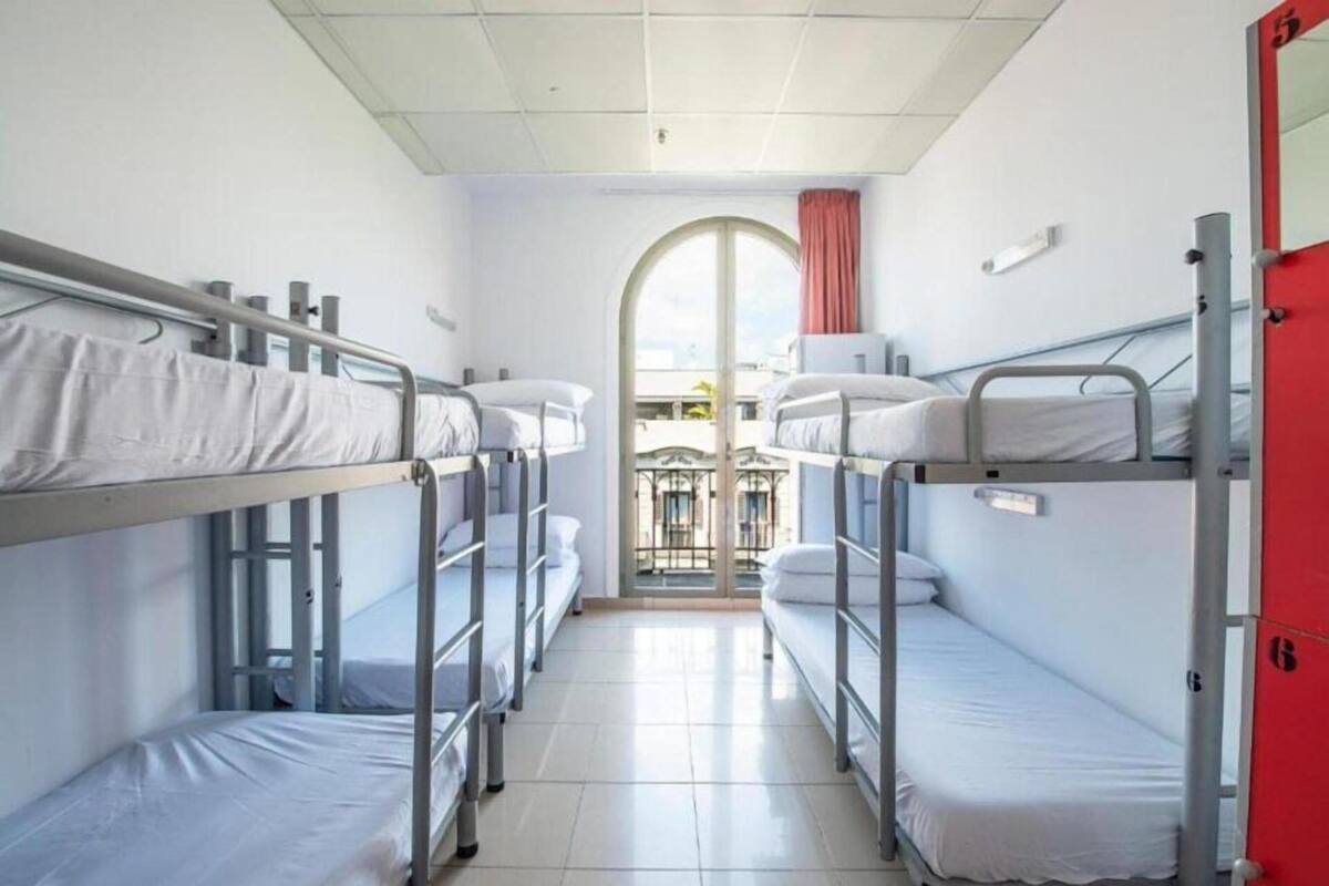 A corridor with bunk beds, a red door, and a window with a view.
