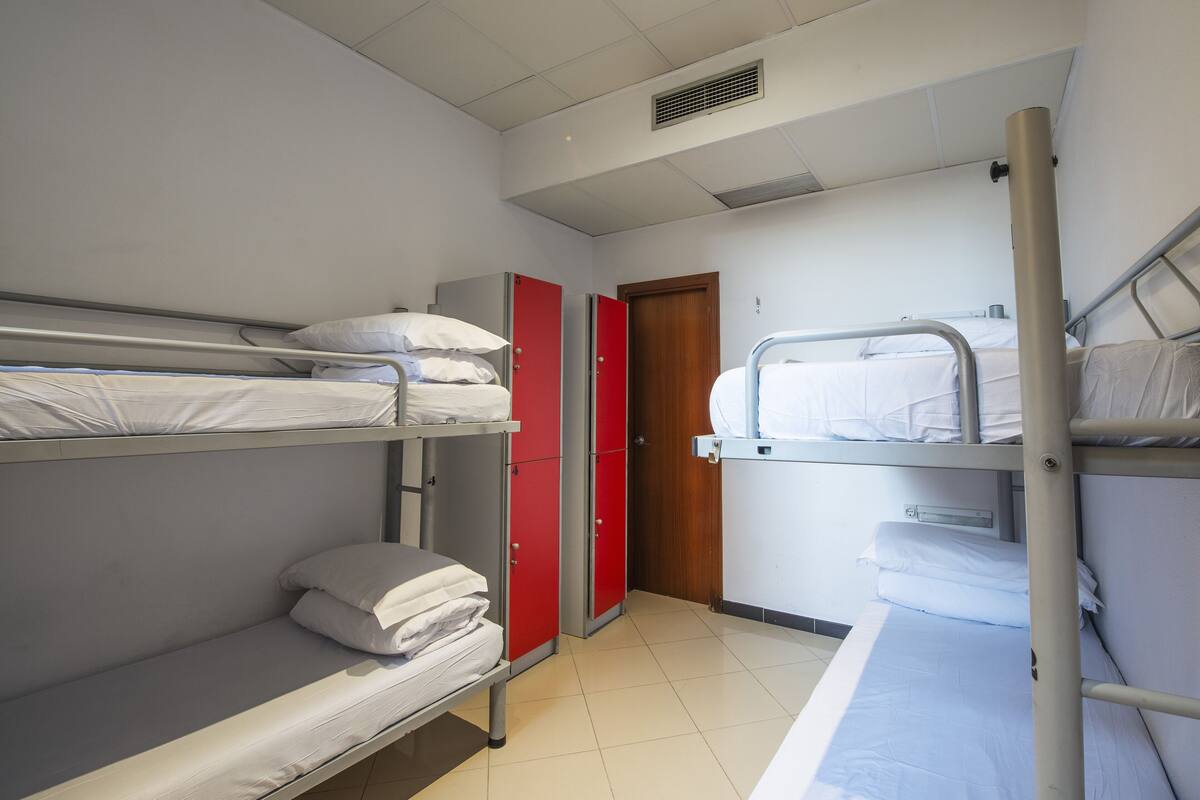 A dormitory room with bunk beds, a red wardrobe, and a wooden door.