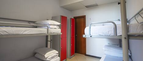 A dormitory room with bunk beds, a red wardrobe, and a wooden door.