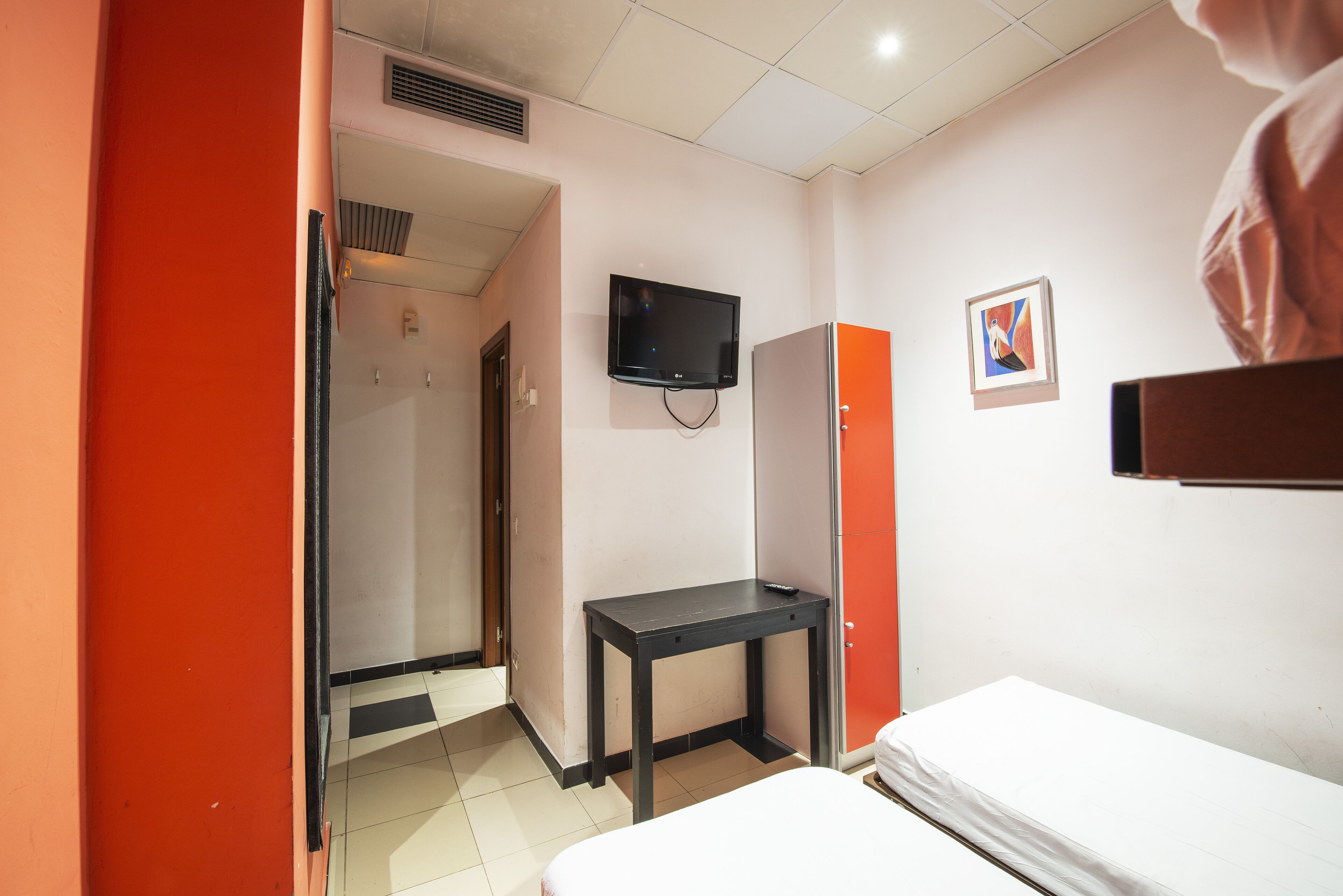 Una habitación de hotel con una cama, un escritorio, un televisor y un armario.