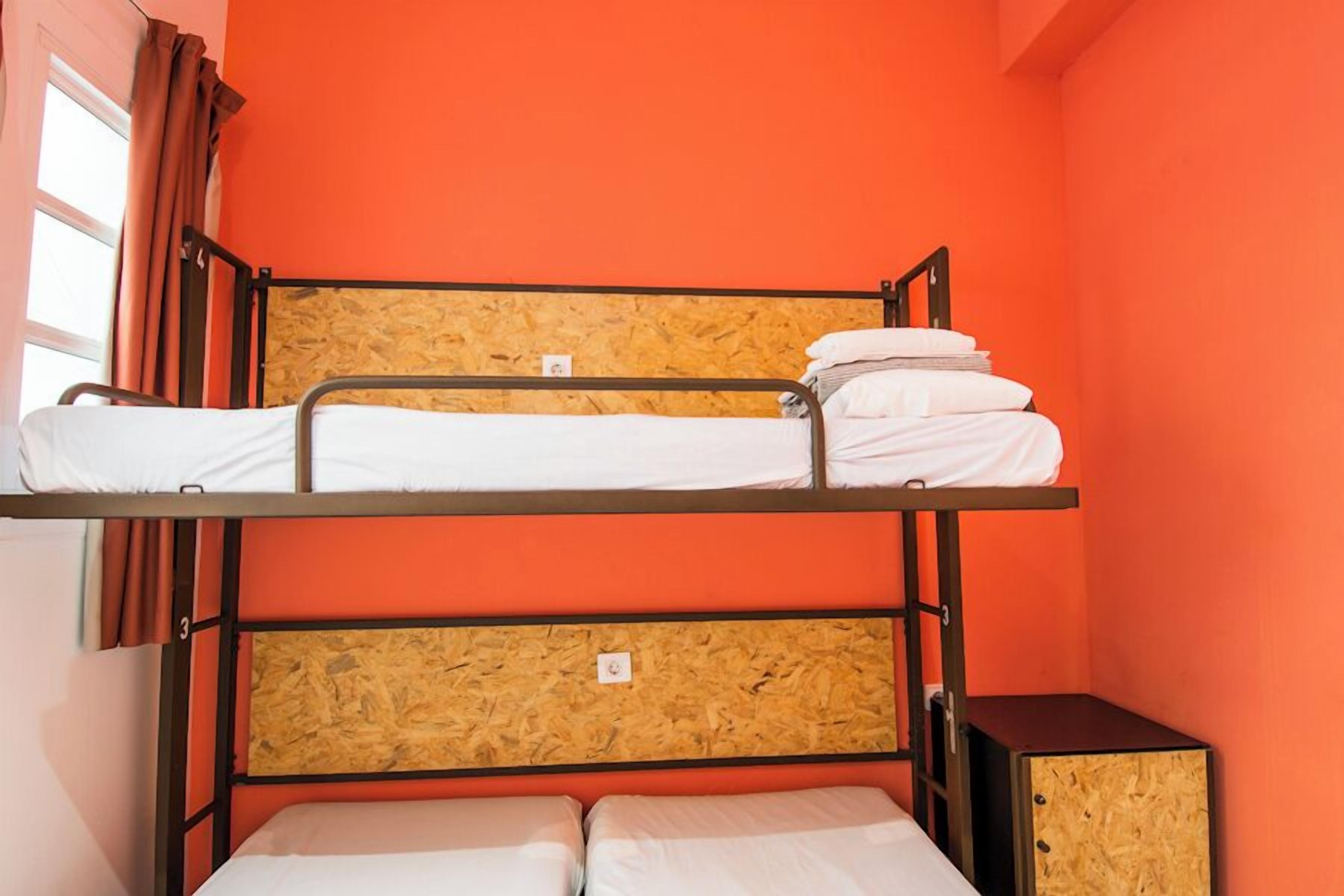 A bunk bed room with orange walls and a wooden headboard.