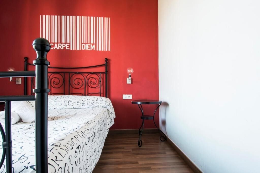 Een kamer met een bed, een klein tafeltje en een wand met een barcode-ontwerp.