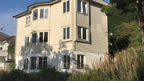 A multi-story building with a corner design, featuring multiple windows and a visible antenna. - Stay.plus Budget Paradis (Bergen)